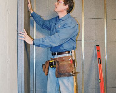 Insulated basement wall panels being placed against a concrete foundation wall in Newbury Park